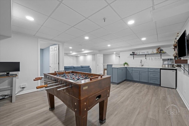 recreation room featuring wet bar, a sink, baseboards, light wood finished floors, and recessed lighting