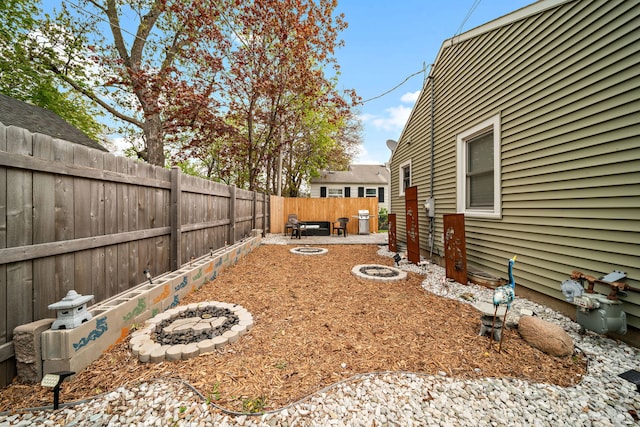 fenced backyard with a fire pit