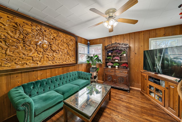 living room with ceiling fan, wood walls, and wood finished floors