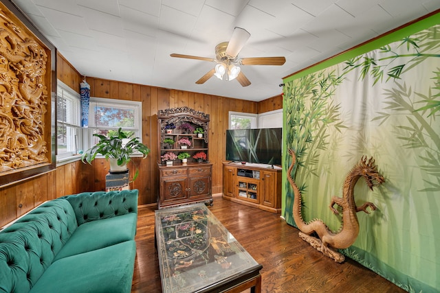 living room with healthy amount of natural light, wood walls, a ceiling fan, and wood finished floors