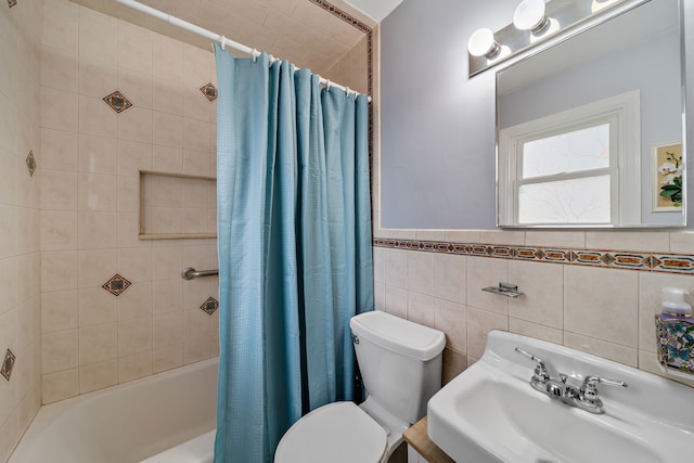 full bath with a sink, toilet, shower / bath combo with shower curtain, wainscoting, and tile walls