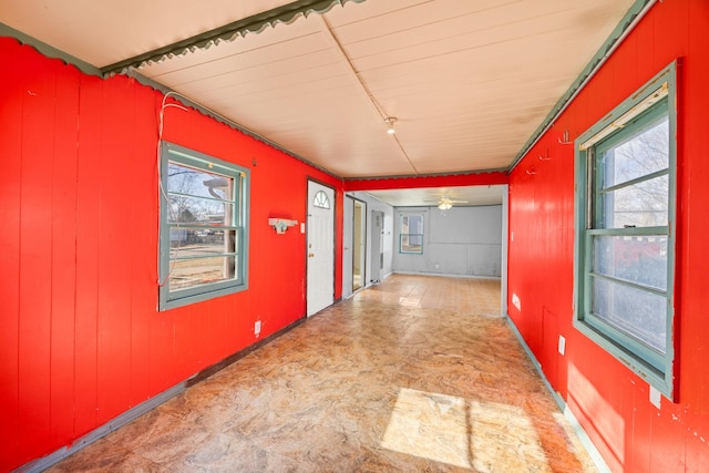 hall with wooden walls, tile patterned floors, and a healthy amount of sunlight