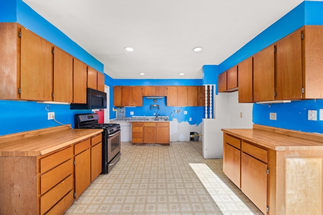 kitchen featuring a sink, black microwave, light countertops, stainless steel gas stove, and light floors
