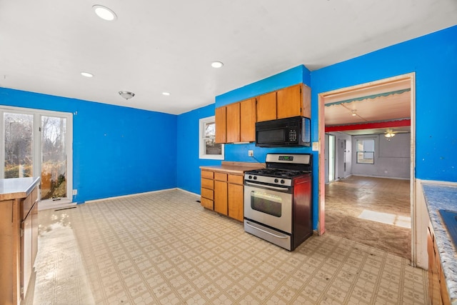 kitchen with black microwave, ceiling fan, gas range, and plenty of natural light
