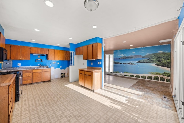 kitchen with a sink, stove, a water view, and brown cabinetry