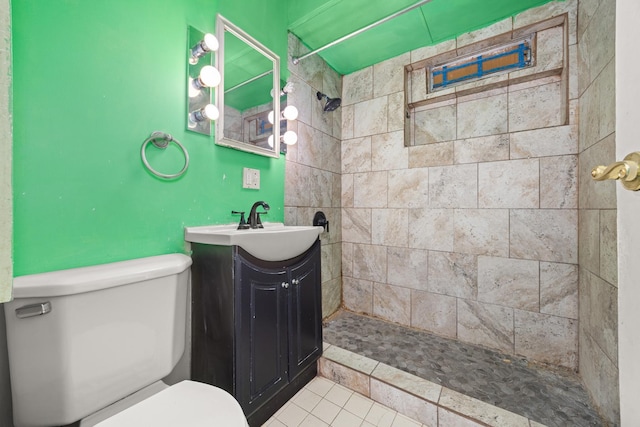 full bathroom with a tile shower, toilet, tile patterned flooring, and vanity
