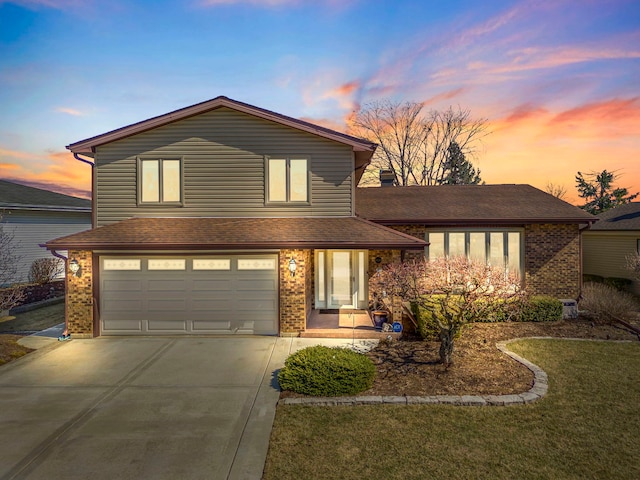 view of front of house featuring a lawn, driveway, an attached garage, and brick siding