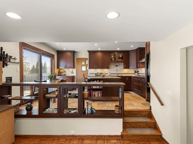 kitchen featuring glass insert cabinets, light countertops, dark brown cabinetry, recessed lighting, and stainless steel fridge
