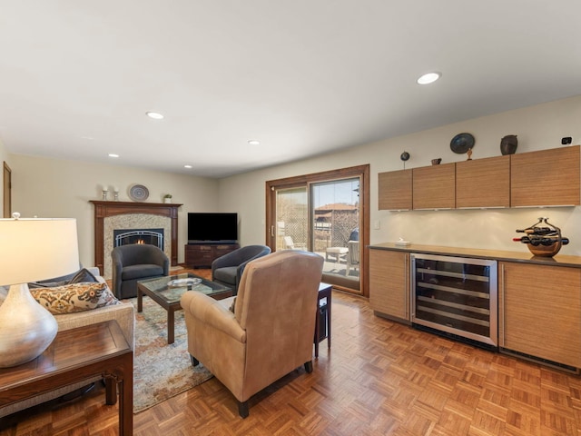 living area featuring beverage cooler, a warm lit fireplace, recessed lighting, and indoor bar