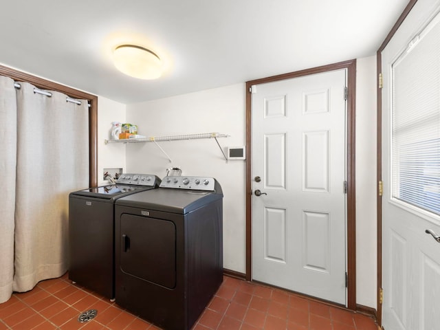 clothes washing area with dark tile patterned floors, washing machine and clothes dryer, and laundry area