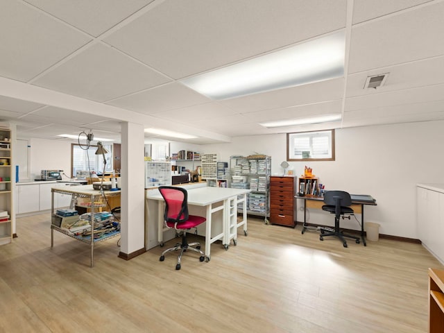 home office with baseboards, visible vents, light wood-style floors, and a drop ceiling