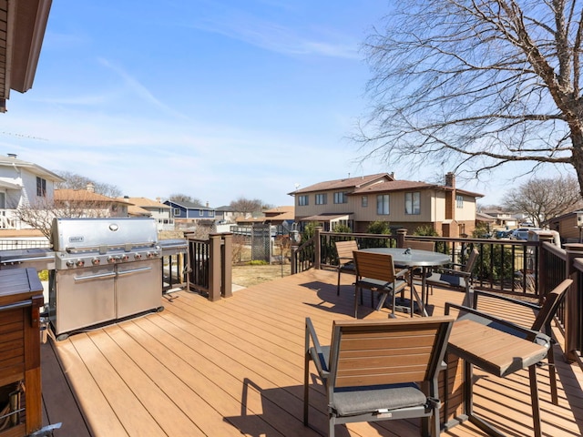 wooden deck with outdoor dining space, grilling area, and a residential view