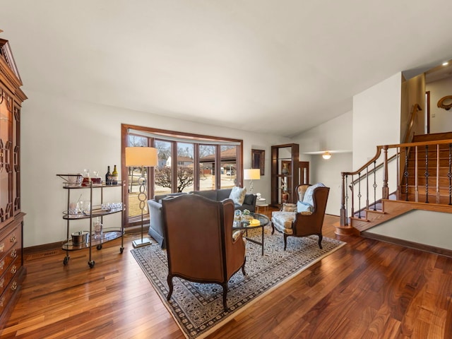 living area featuring stairs, lofted ceiling, wood finished floors, and baseboards