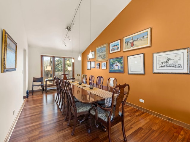 dining space with dark wood-style floors, rail lighting, lofted ceiling, and baseboards