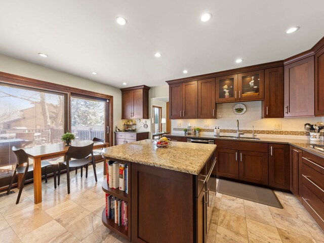 kitchen with tasteful backsplash, recessed lighting, light stone counters, a sink, and a center island