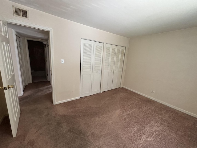 unfurnished bedroom featuring carpet flooring, two closets, visible vents, and baseboards