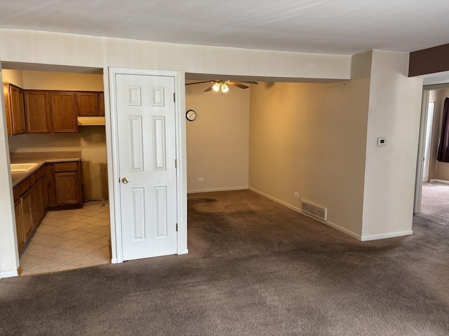 interior space with light colored carpet, visible vents, baseboards, and ceiling fan