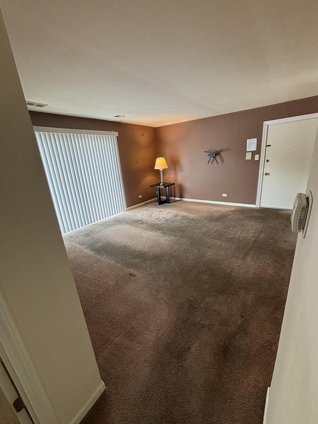 unfurnished room with carpet, visible vents, and baseboards