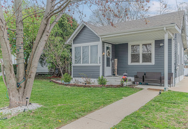 bungalow featuring a porch, a front lawn, and roof with shingles