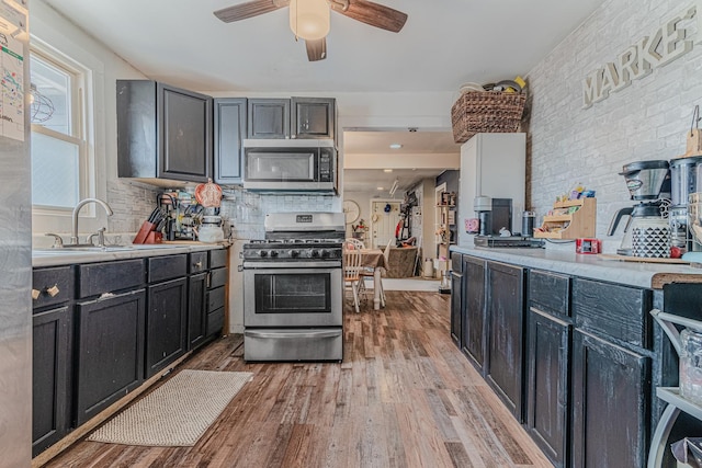 kitchen with appliances with stainless steel finishes, light countertops, ceiling fan, light wood finished floors, and a sink