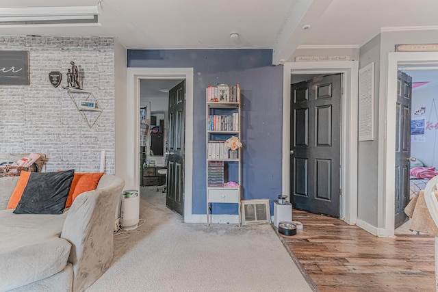 interior space with baseboards, visible vents, wood finished floors, and brick wall