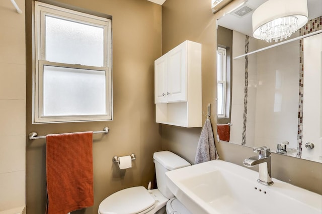 full bathroom featuring visible vents, toilet, tiled shower, and a sink