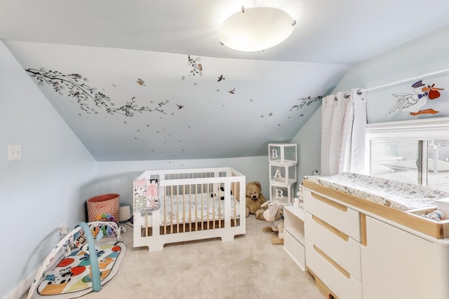 bedroom with a crib, light colored carpet, and lofted ceiling