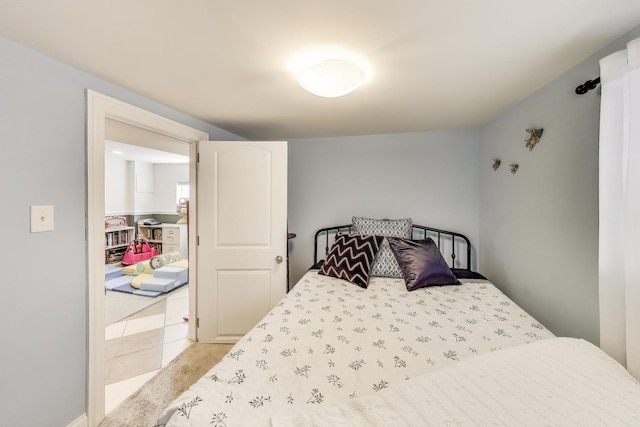 bedroom with light tile patterned floors and light carpet