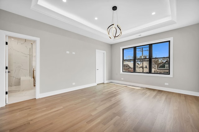 unfurnished room featuring recessed lighting, a tray ceiling, and light wood-type flooring