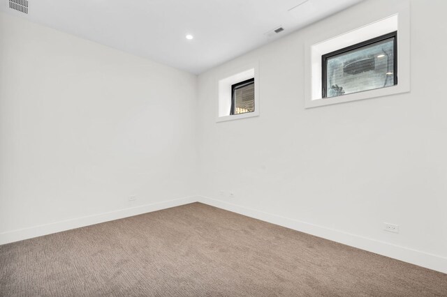 empty room featuring carpet floors, baseboards, recessed lighting, and visible vents