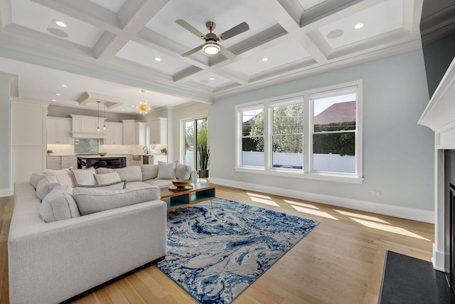 living area with coffered ceiling, baseboards, light wood finished floors, ceiling fan, and beamed ceiling