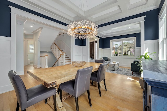 dining area featuring a chandelier, a decorative wall, stairway, ornamental molding, and light wood-style flooring