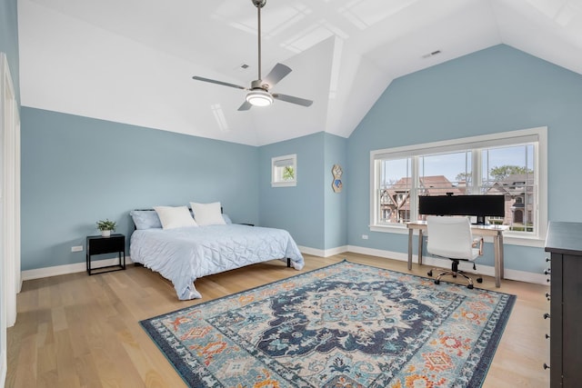 bedroom with vaulted ceiling, an office area, wood finished floors, baseboards, and ceiling fan