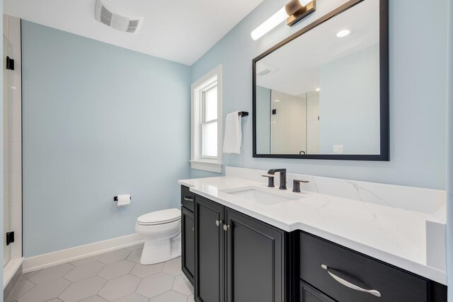 bathroom featuring baseboards, a shower stall, toilet, vanity, and tile patterned floors