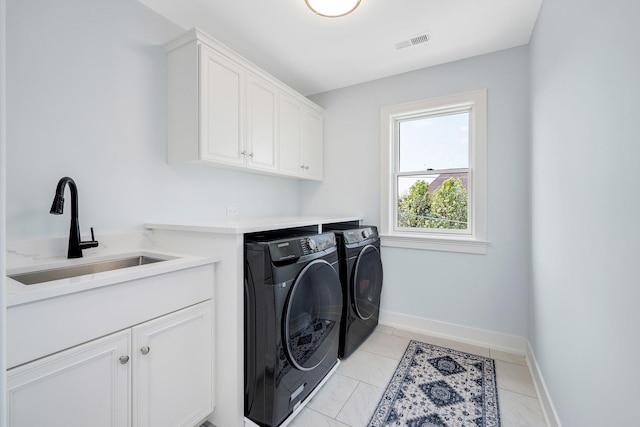 washroom featuring cabinet space, independent washer and dryer, baseboards, and light tile patterned floors