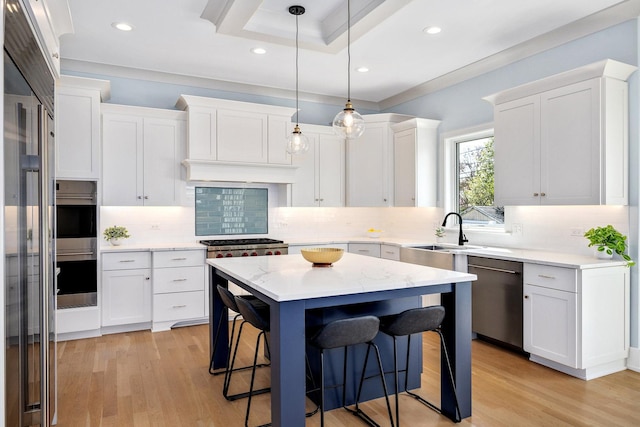 kitchen with stainless steel appliances, a sink, a kitchen bar, white cabinetry, and recessed lighting
