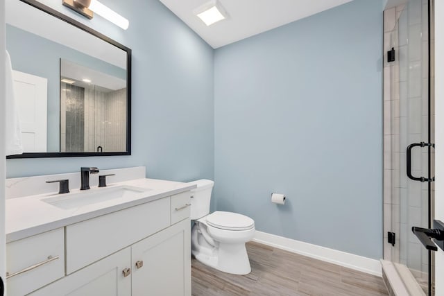 full bathroom featuring baseboards, a stall shower, wood finished floors, toilet, and vanity