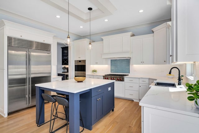 kitchen with appliances with stainless steel finishes, a center island, light wood-style flooring, tasteful backsplash, and white cabinets