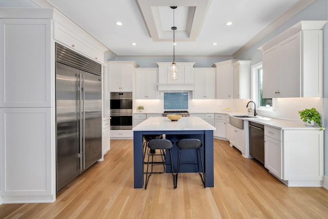 kitchen with stainless steel appliances, a sink, a center island, light wood finished floors, and decorative backsplash