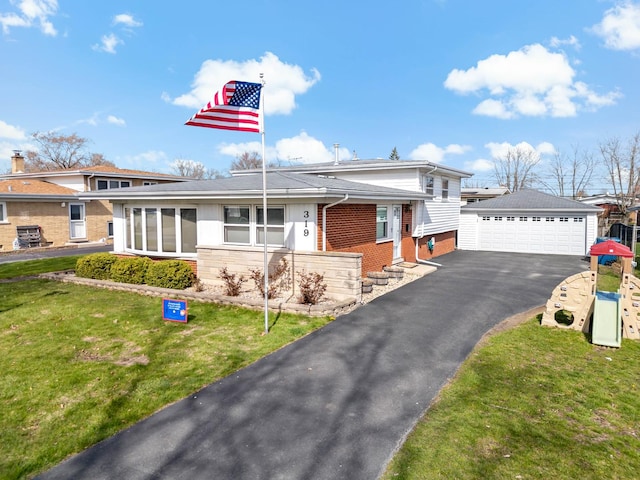view of front of home with a detached garage, a front yard, brick siding, and an outbuilding