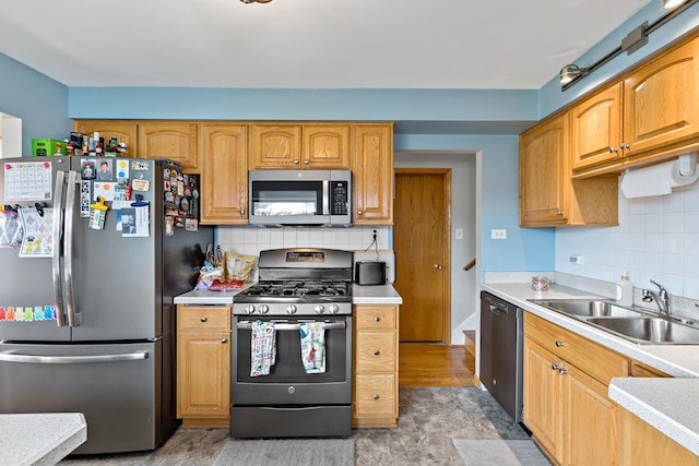 kitchen featuring stainless steel appliances, backsplash, light countertops, and a sink