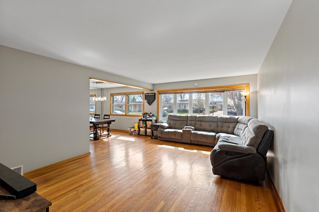 living area with a chandelier, baseboards, and light wood-style flooring