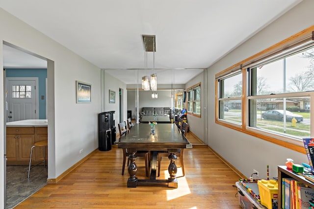dining room featuring a notable chandelier, baseboards, light wood-style floors, and plenty of natural light