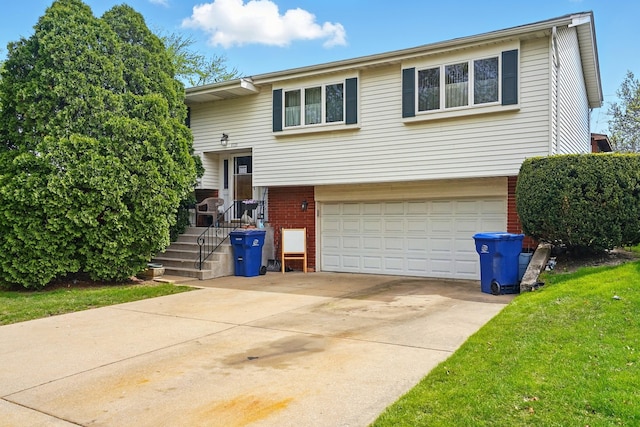 raised ranch with concrete driveway, brick siding, and a garage