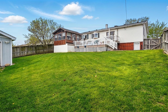 rear view of property featuring a fenced backyard, a sunroom, a wooden deck, and a yard