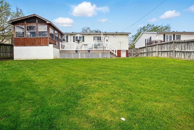rear view of property featuring a fenced backyard, a yard, a sunroom, and a deck
