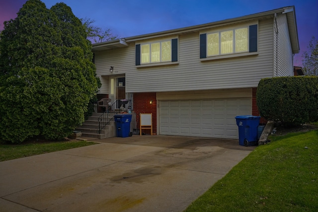 split foyer home with concrete driveway, brick siding, and an attached garage