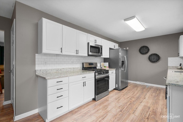 145 W Eisenhower St, Waterman, IL 60556 - kitchen with white cabinets, appliances with stainless steel finishes, light wood-style floors, baseboards, and backsplash