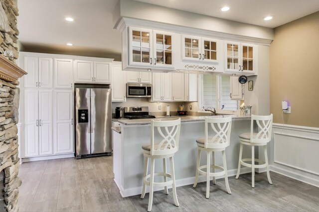 2502 S Hidden Trl, Spring Grove, IL 60081 - kitchen with light wood finished floors, a breakfast bar area, glass insert cabinets, white cabinetry, and appliances with stainless steel finishes