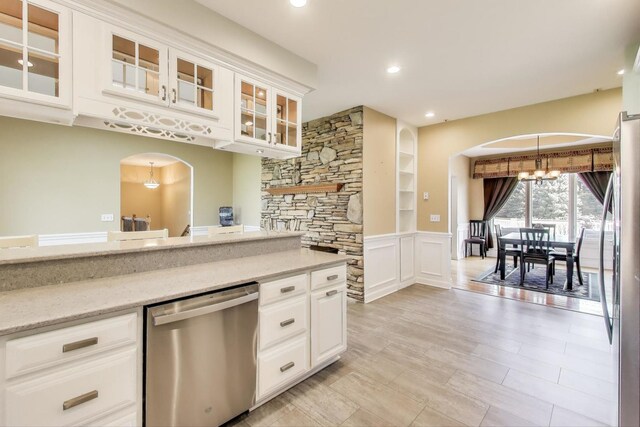 2502 S Hidden Trl, Spring Grove, IL 60081 - kitchen with light stone counters, a chandelier, white cabinetry, arched walkways, and stainless steel dishwasher
